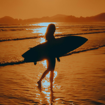Surfer on beach at sunset